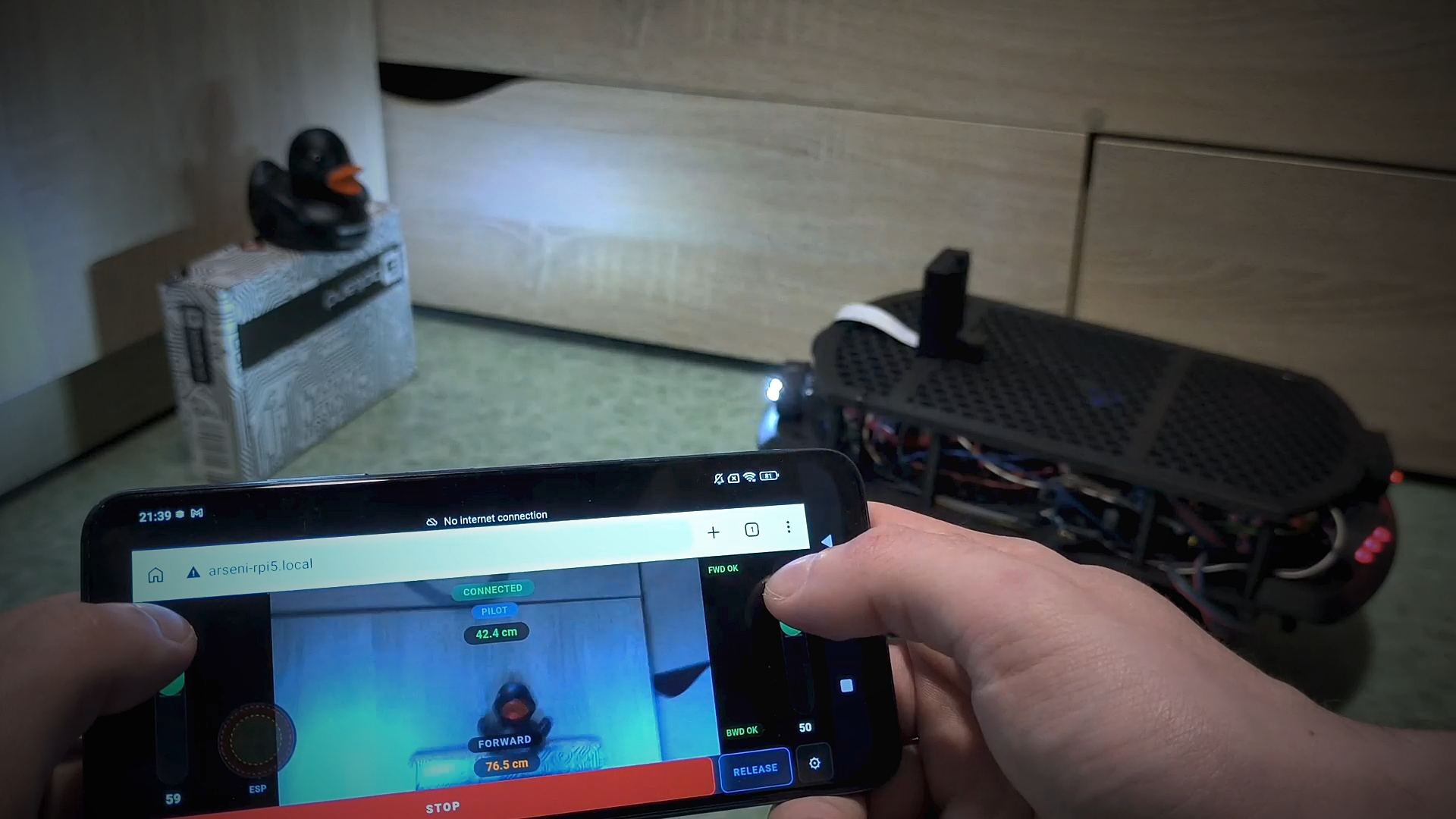 Zero-config robot demo: ESP32 IMU tilt controller in hand, robot responding to tilt gestures in real time